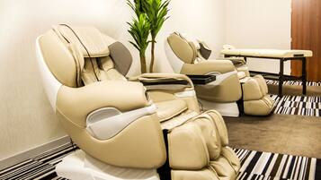 Relax in comfort with two massage therapy chairs, each with a footrest and control panel, and a small table for your convenience.