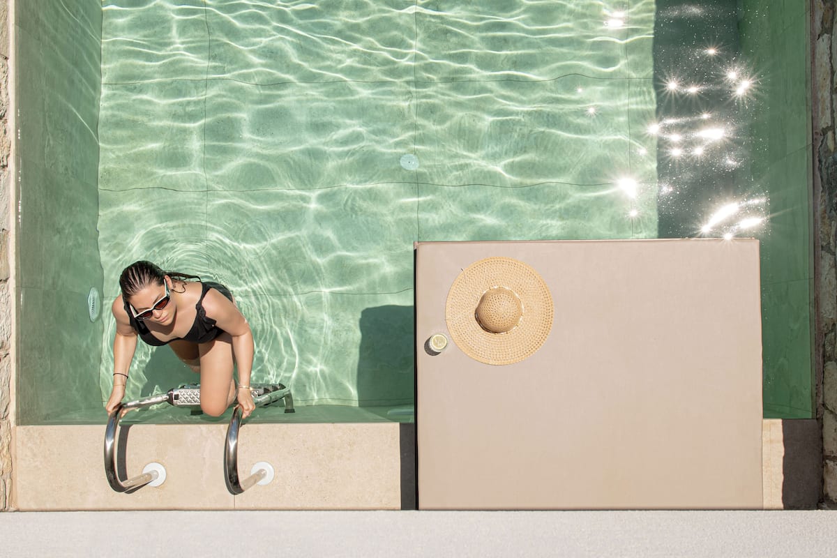 A pool with clear water, a diving board, and a door with a straw hat on it.