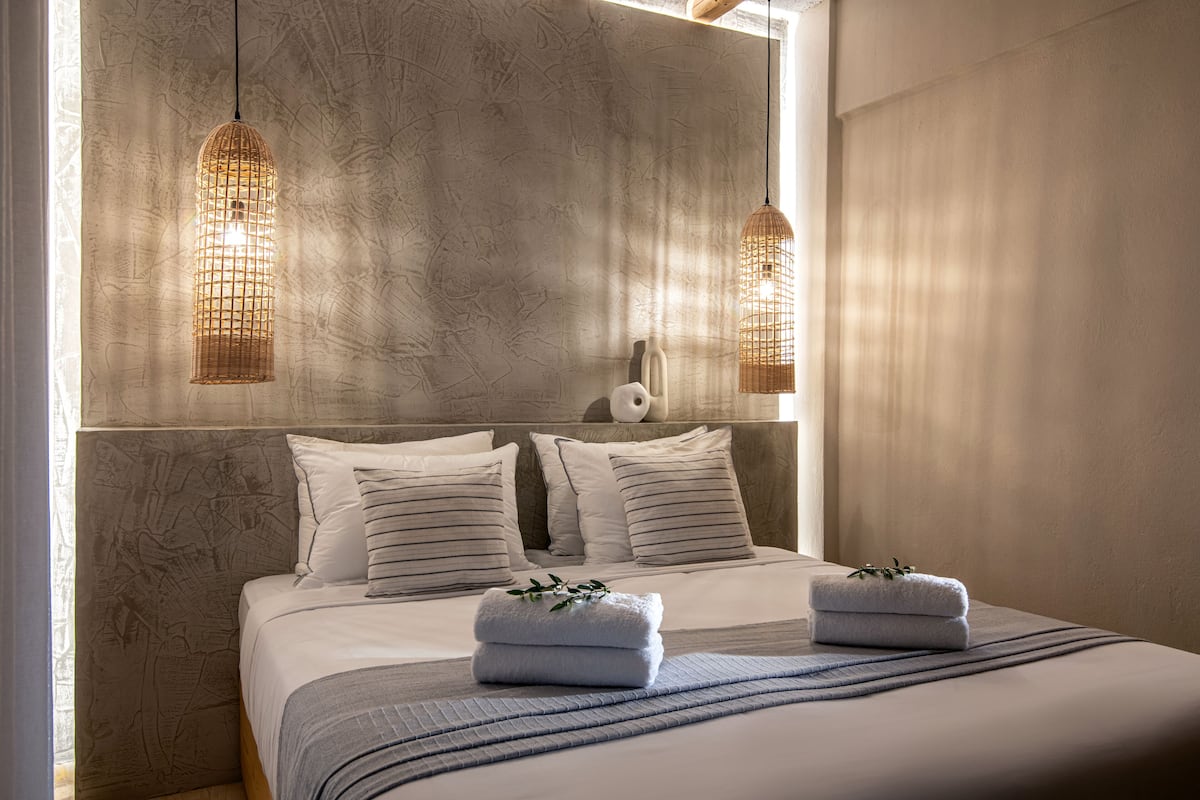 A bedroom with a large bed, two hanging light fixtures, and a textured wall.