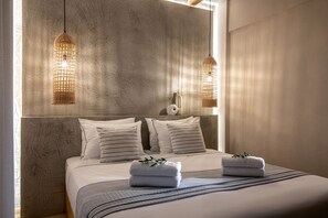 Ein Schlafzimmer mit einem großen Bett, zwei Pendelleuchten und einer strukturierten Wand.
