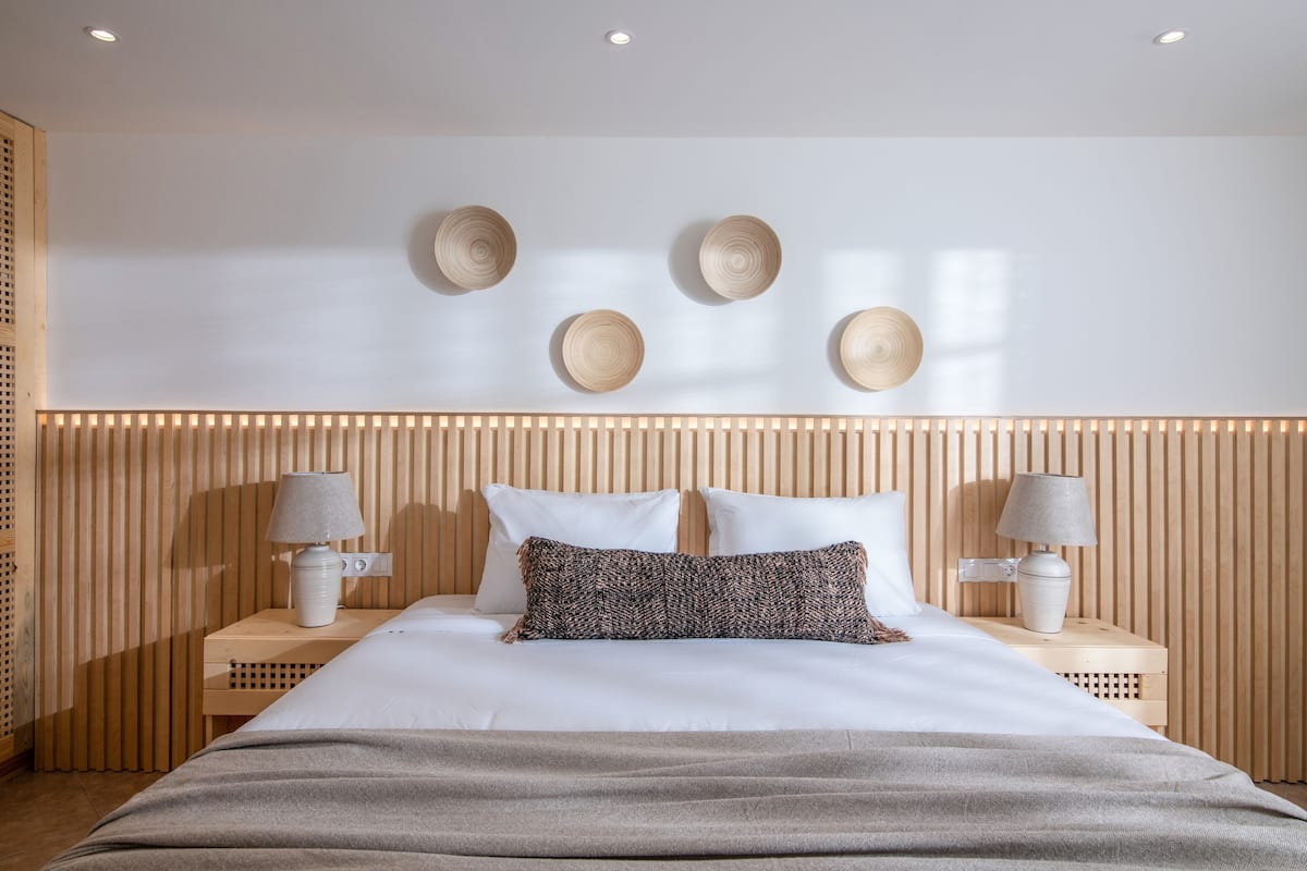 A neatly arranged bedroom with a large bed, two bedside tables with lamps, and a wall-mounted light fixture.