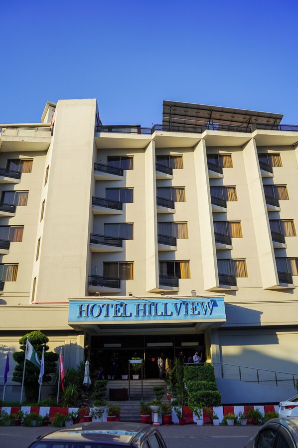 Un hotel con varios balcones, techo plano y un letrero que dice 'HOTEL HILLVIEW'.