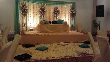 A stage with a sofa and chairs, decorated with flowers and drapes.