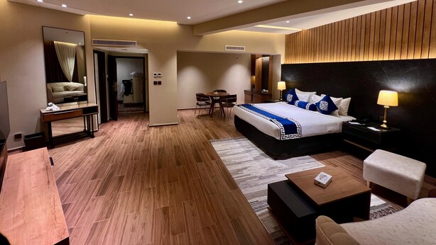 Ein Hotelzimmer mit einem großen Bett, einem Schreibtisch, einem Sessel, einem kleinen Tisch, einer Couch und einem Spiegel.
