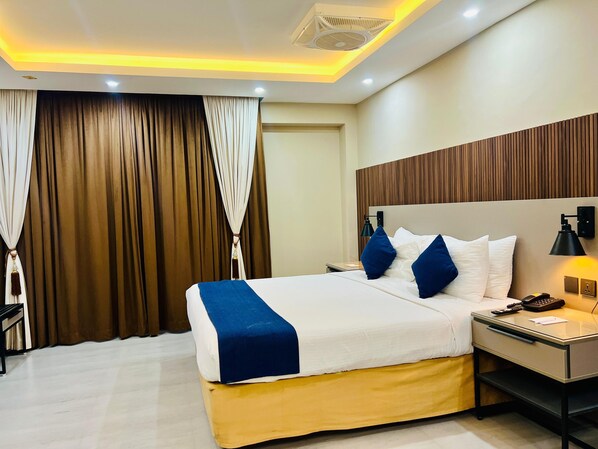 Una habitación de hotel con cama, mesita de noche, lámpara y cortinas.