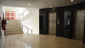 Eine saubere, moderne Lobby mit Treppe, Aufzügen und einem Feuerlöscher.