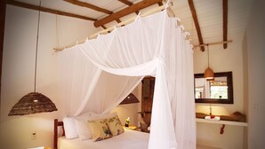 A bedroom with a canopy bed, a bedside table, a hanging light, and a mirror on the wall. - Biribandos Rooms by Trancoso House (Porto Seguro)