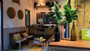 A cozy living room with a sofa, coffee table, and a large plant. - Biribandos Rooms by Trancoso House (Porto Seguro)