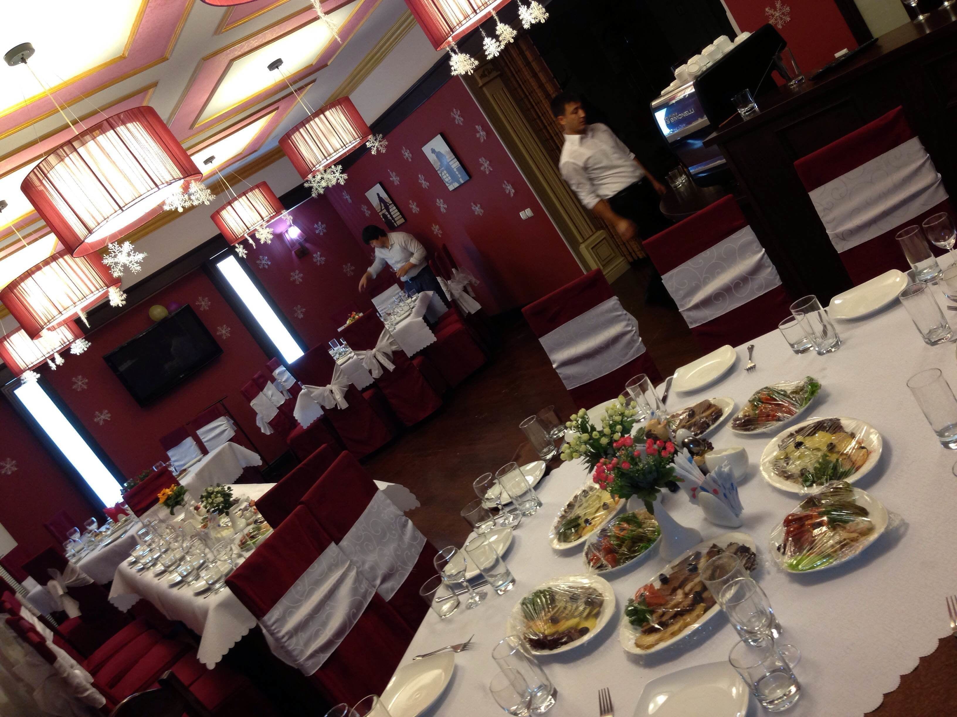 A restaurant with tables set for dining, red upholstered chairs, and a ceiling with decorative lighting.