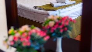 A hotel room with a bed, a nightstand, a lamp, and a vase with flowers. - Hotel San Marino (Astana)