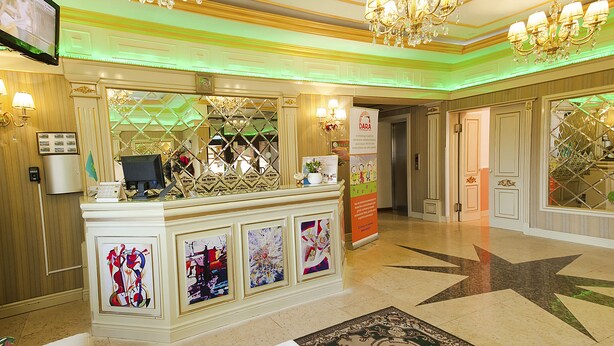 A reception area with a counter, chandeliers, and framed artwork. - Hotel San Marino (Astana)