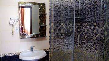 A bathroom with a white sink, a mirror with a gold frame, and a shower with mosaic tiles.