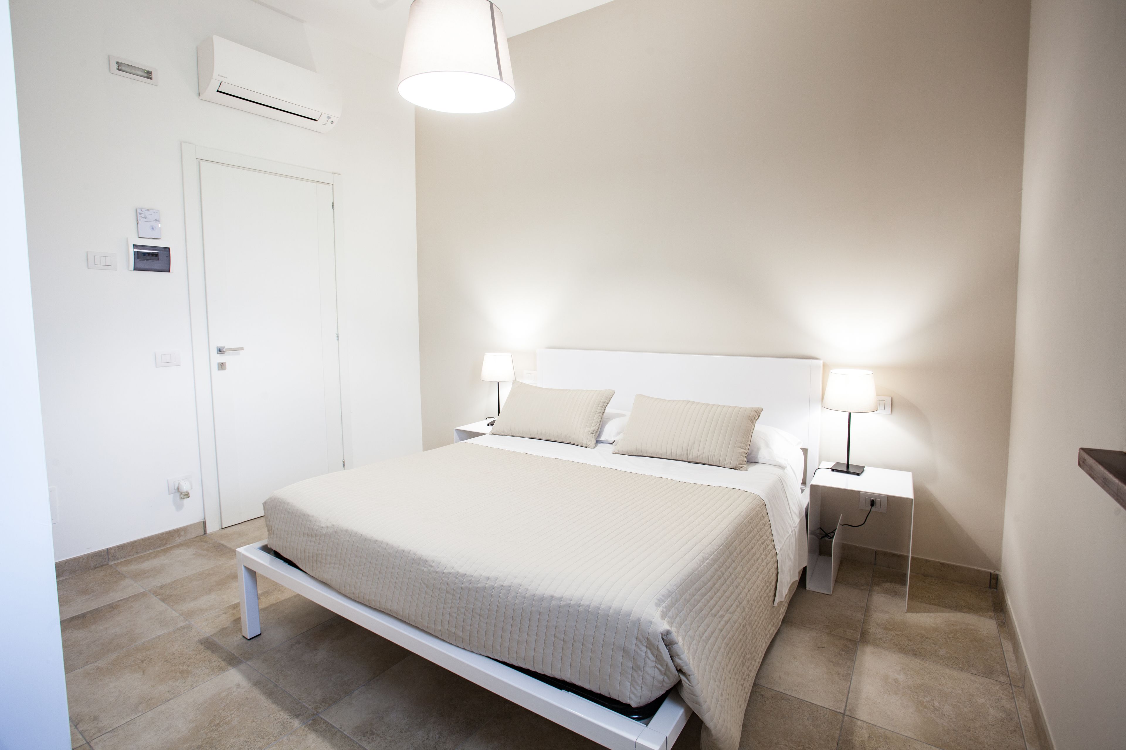 Een keurig opgemaakt slaapkamer met een bed, nachtkastjes en een lamp.