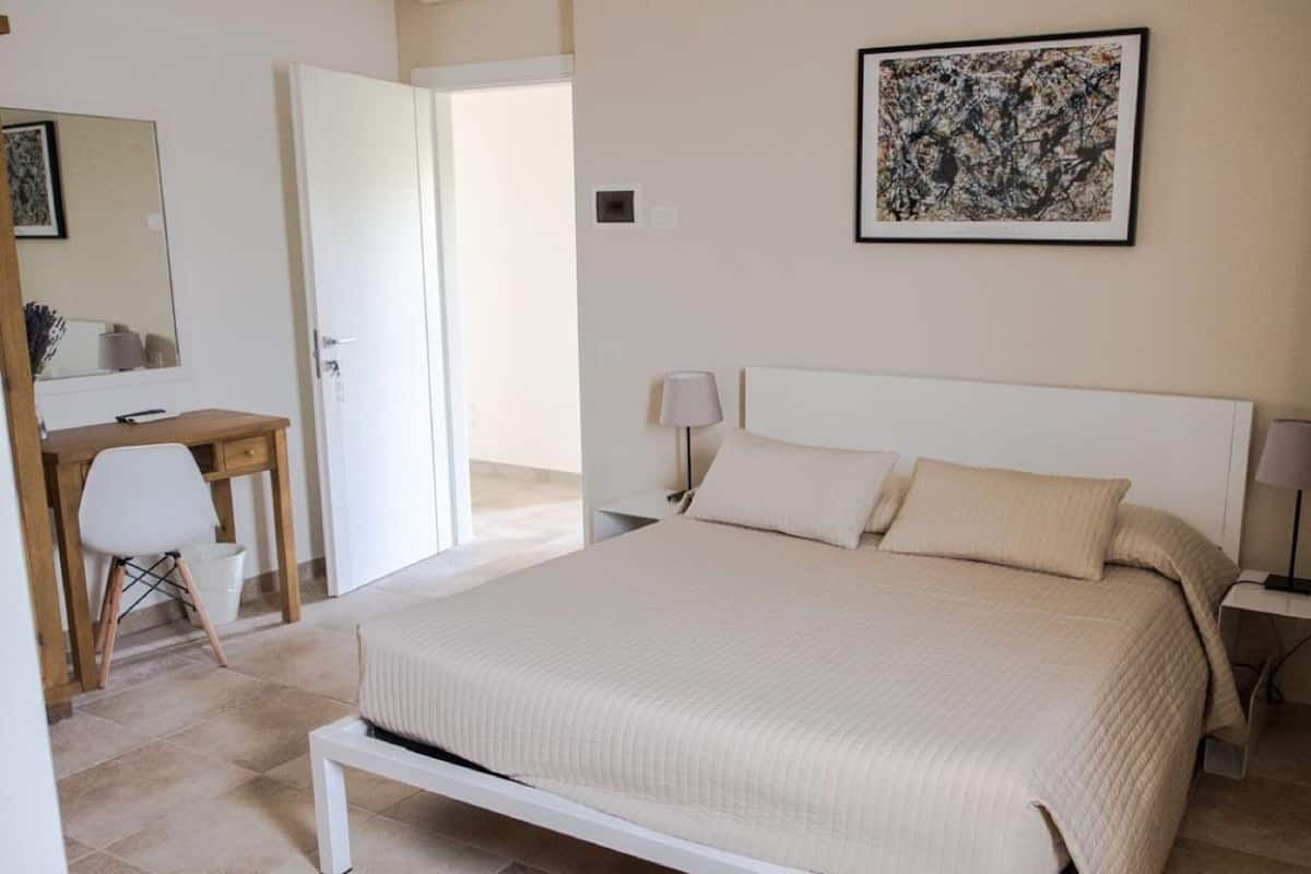 A bedroom with a bed, bedside tables, a desk, and a chair.