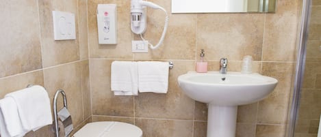 Un baño con inodoro, bidé, lavabo y ducha.