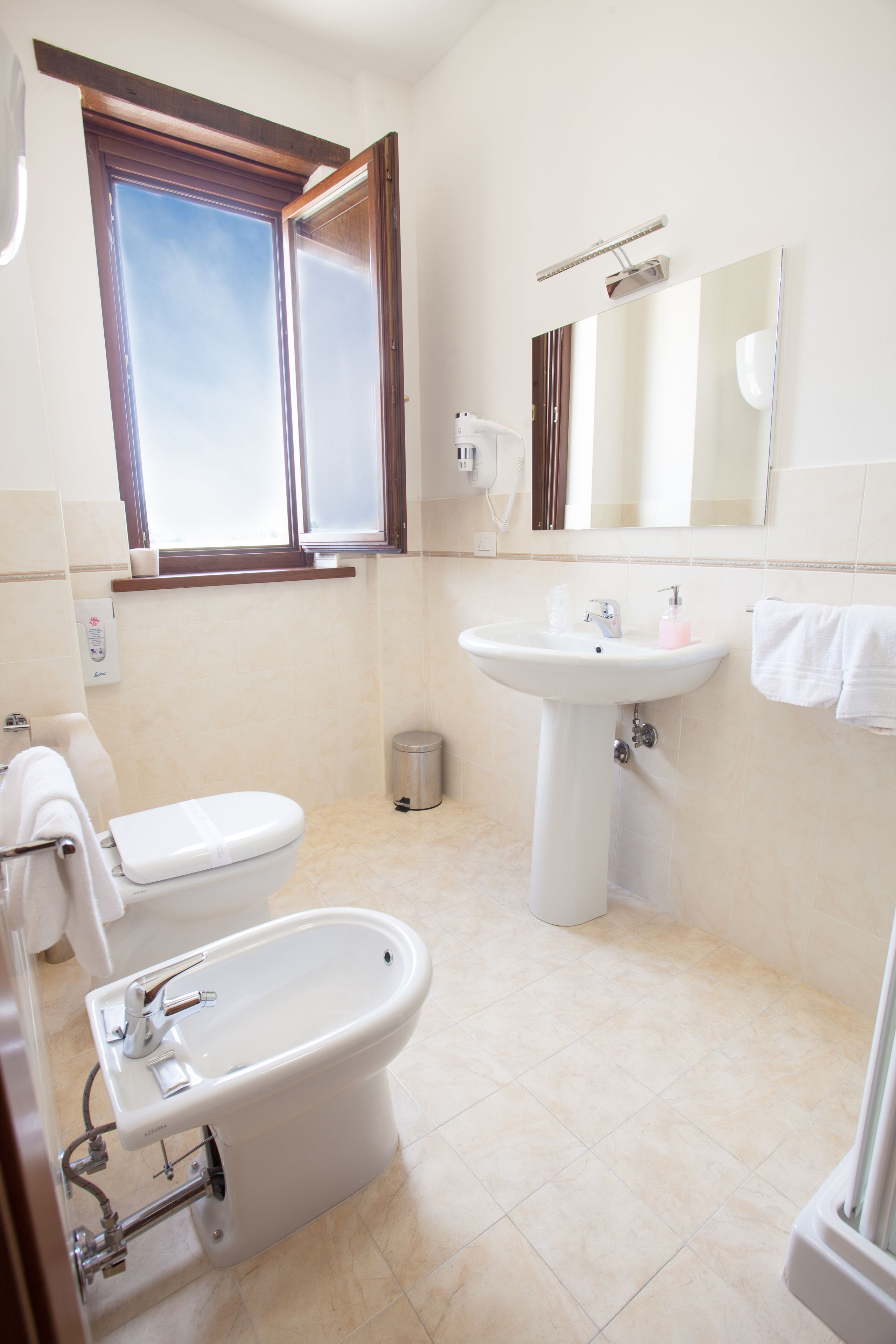 Un baño con inodoro, bidé, lavabo y espejo.