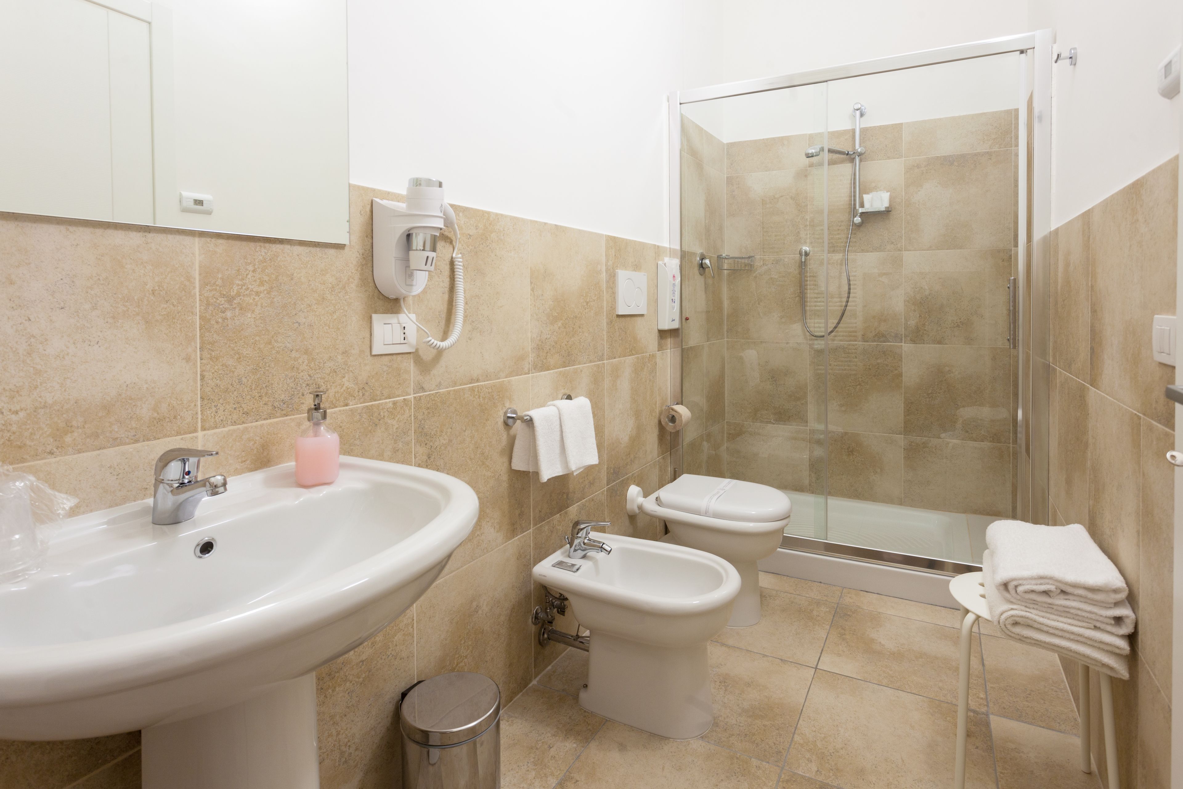 A bathroom with a sink, bidet, toilet, and glass-enclosed shower.