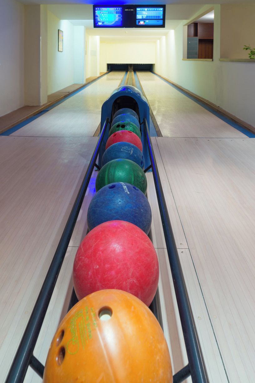 A bowling alley with a lane, bowling balls, and a scoreboard.