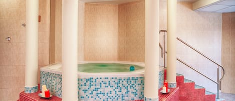 A spa area with a hot tub, red tiled steps, and a tiled wall.