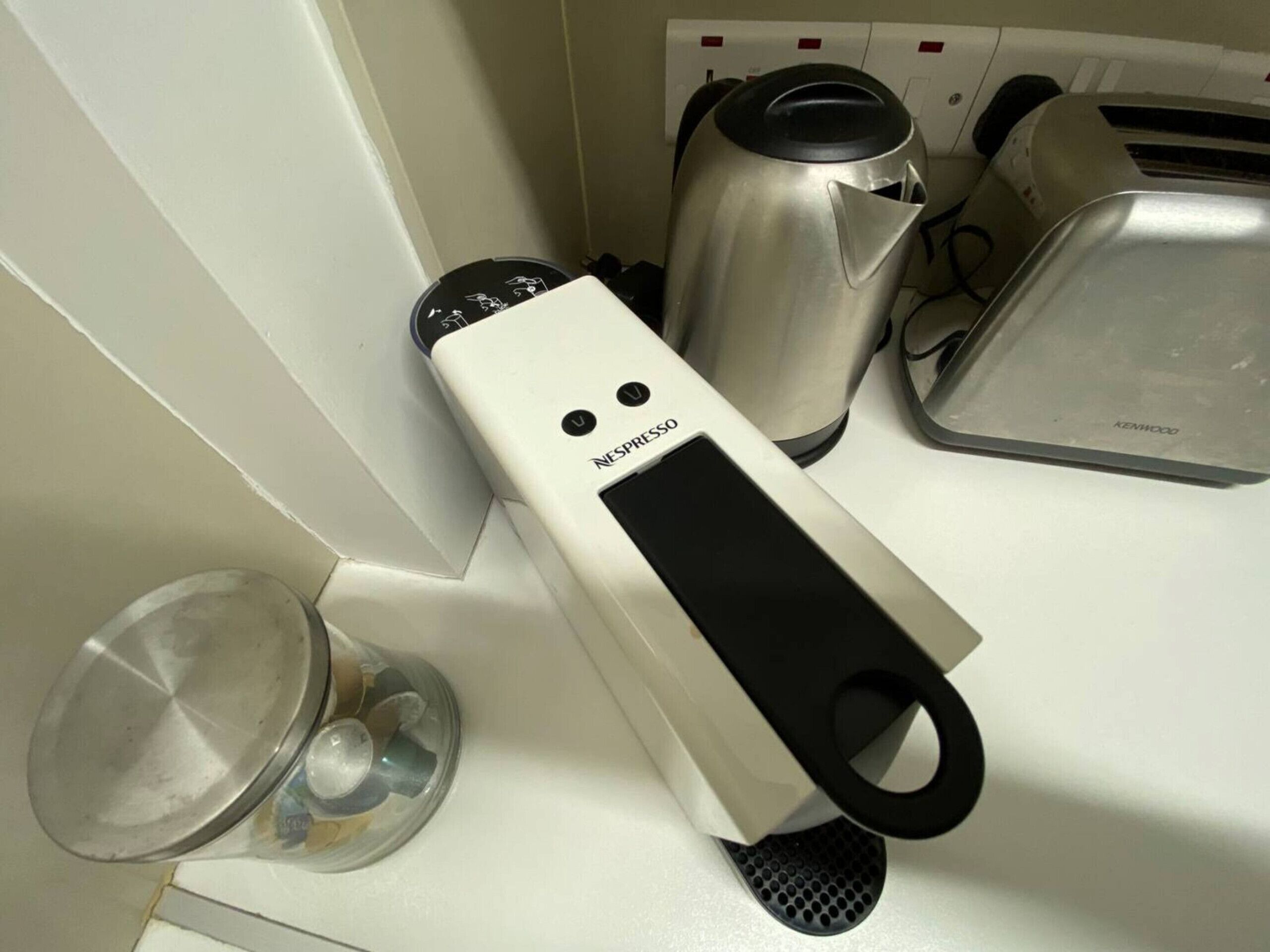 A kitchen with a Nespresso coffee machine, a kettle, a toaster, and a coffee grinder.