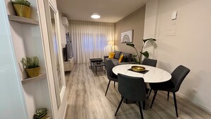 Un comedor moderno con una mesa redonda, sillas negras y una mesita auxiliar.