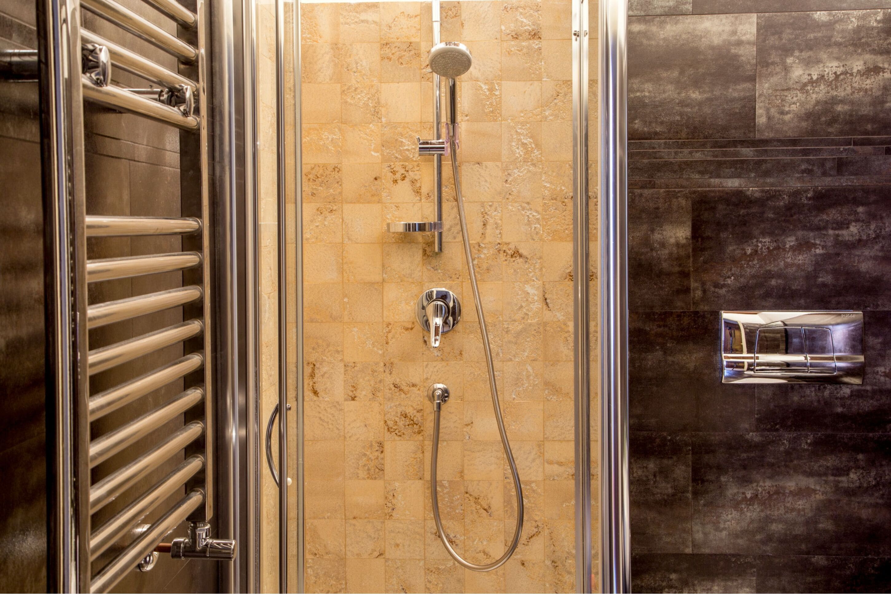 A shower with a handheld showerhead, a wall-mounted faucet, and a handheld showerhead.