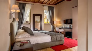 A modern bedroom with a large bed, bedside lamps, a desk, and a television. - Palazzo Medusa (Rome)