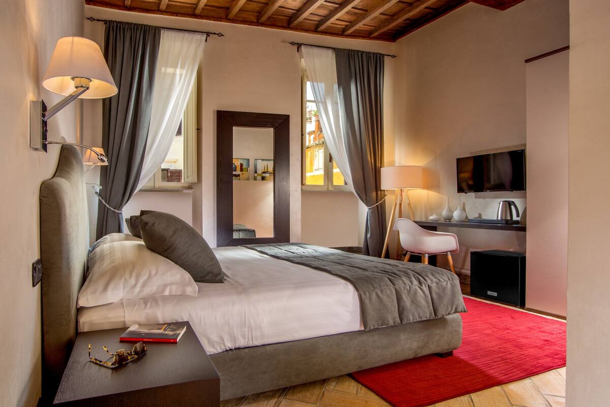 A modern bedroom with a large bed, bedside lamps, a desk, and a television.