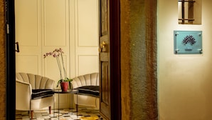 A hotel lobby with a checkered floor, two armchairs, a small table with a potted plant, and a sign on the wall. - Palazzo Medusa (Rome)