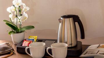 Ein Tisch mit Kaffeemaschine, zwei weißen Tassen, einem Topf mit Orchideen, einer Brieftasche und einer Zeitschrift.