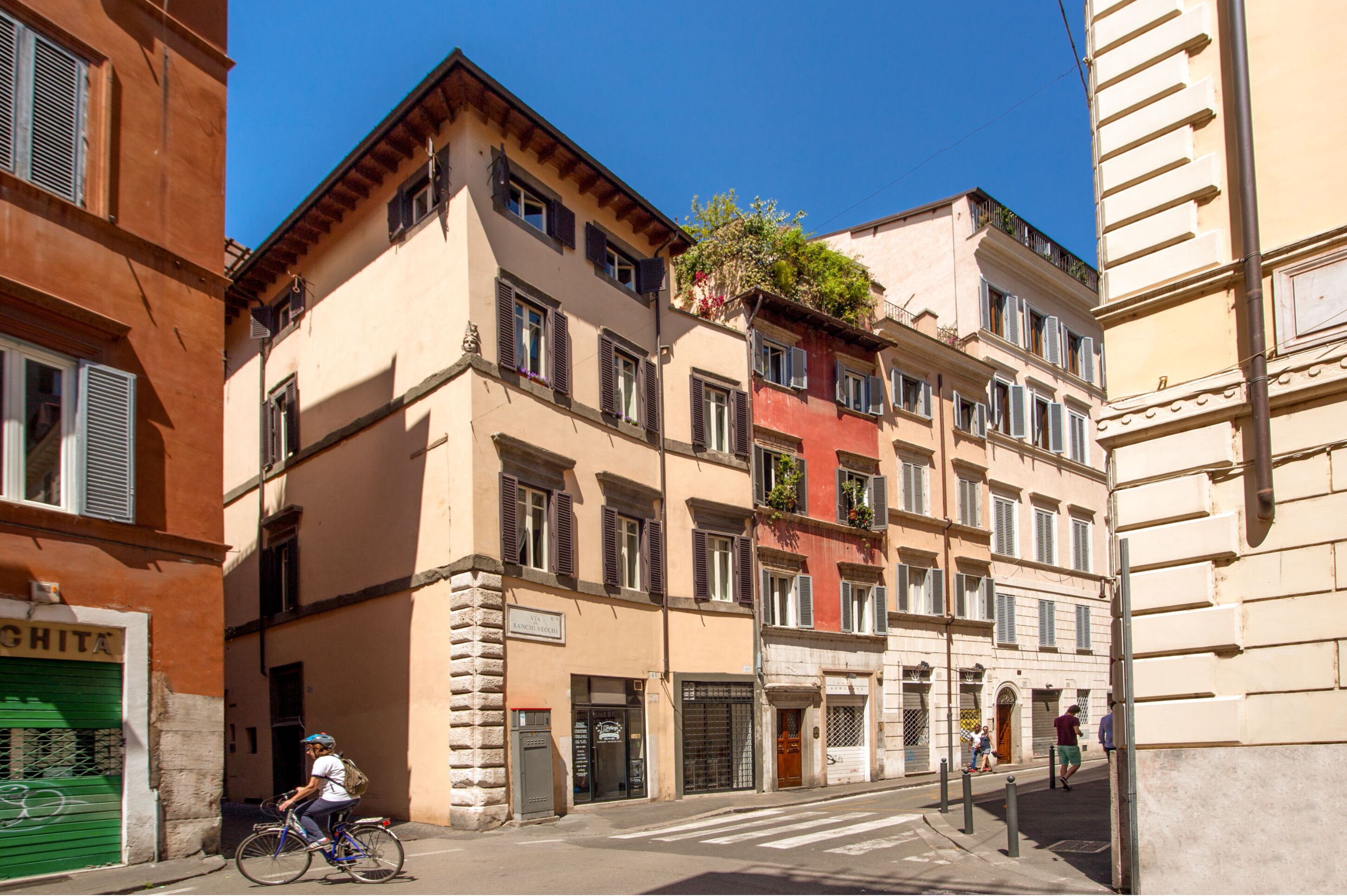 A street with buildings, a cyclist, and pedestrians.