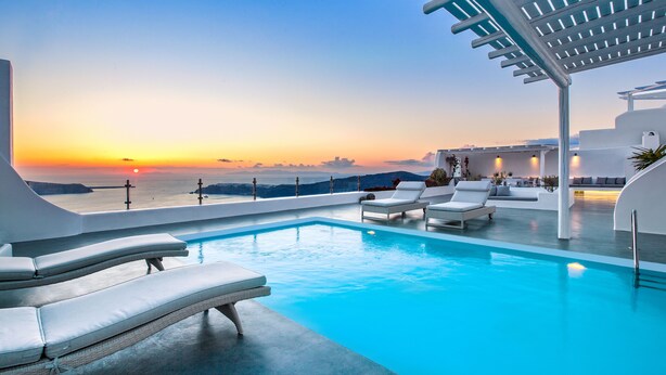 A modern infinity pool with white lounge chairs and a view of the sunset over the sea. - Erossea Villa Santorini Imerovigli (Santorini)