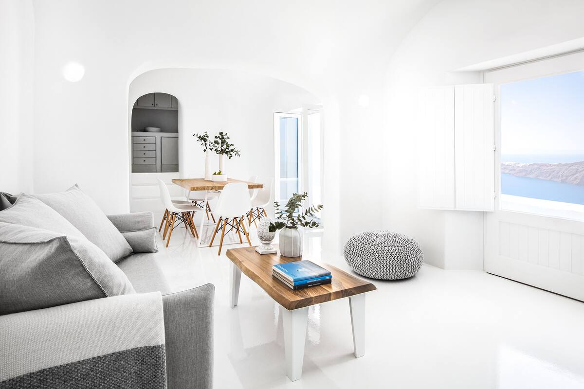 Ein modernes Wohnzimmer mit einer Couch, einem Holztisch und Blick ins Freie.