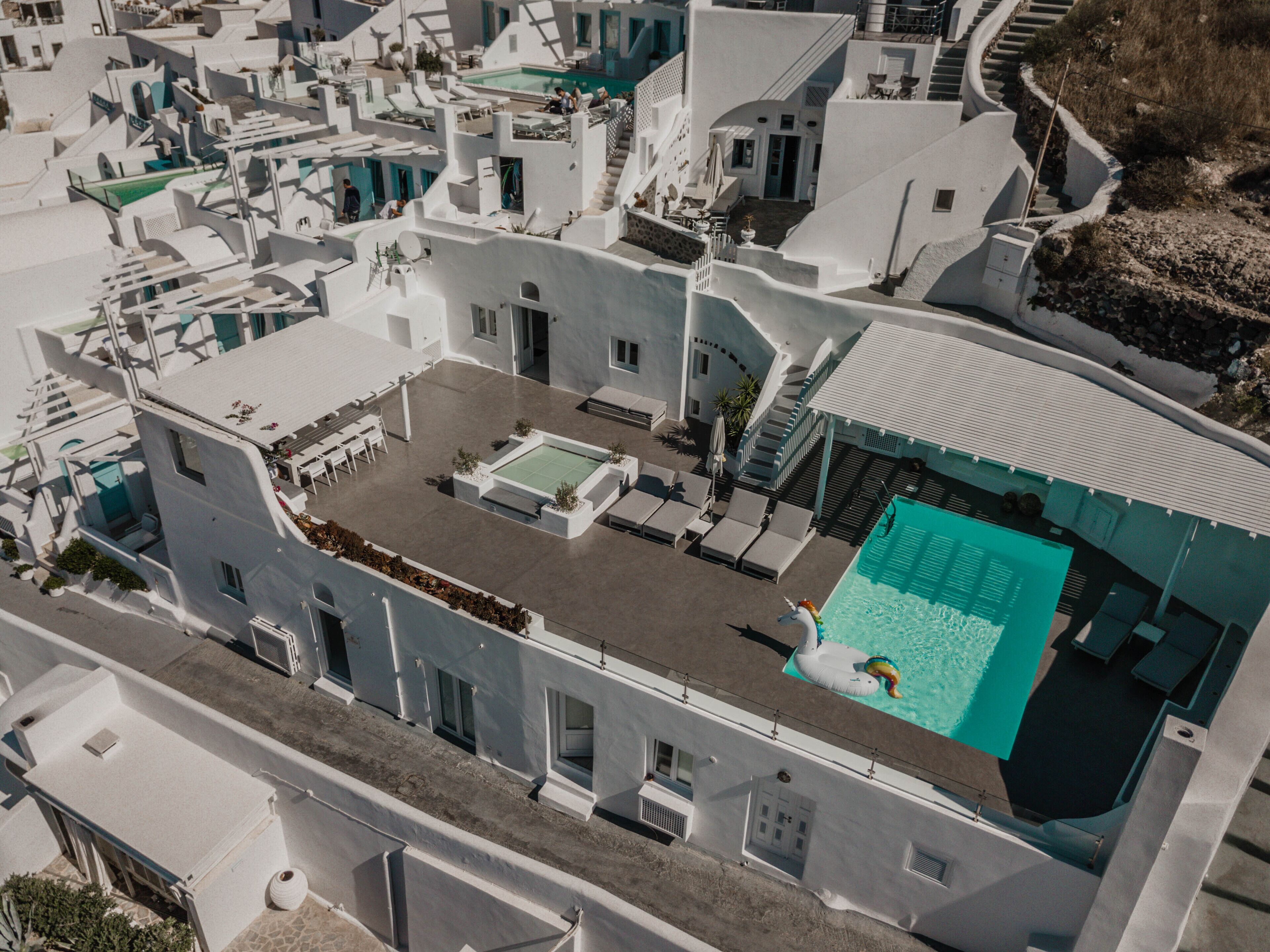 A modern white building with a rooftop pool, outdoor seating, and a staircase leading to a terrace.