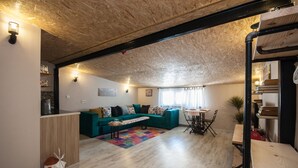 Una sala de estar acogedora con techo de madera, un sofá azul verdoso, una mesa de centro de madera y una alfombra colorida.