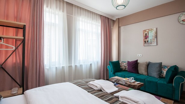 Una habitación de hotel con una cama, un sofá, una mesita de madera y una lámpara colgante.