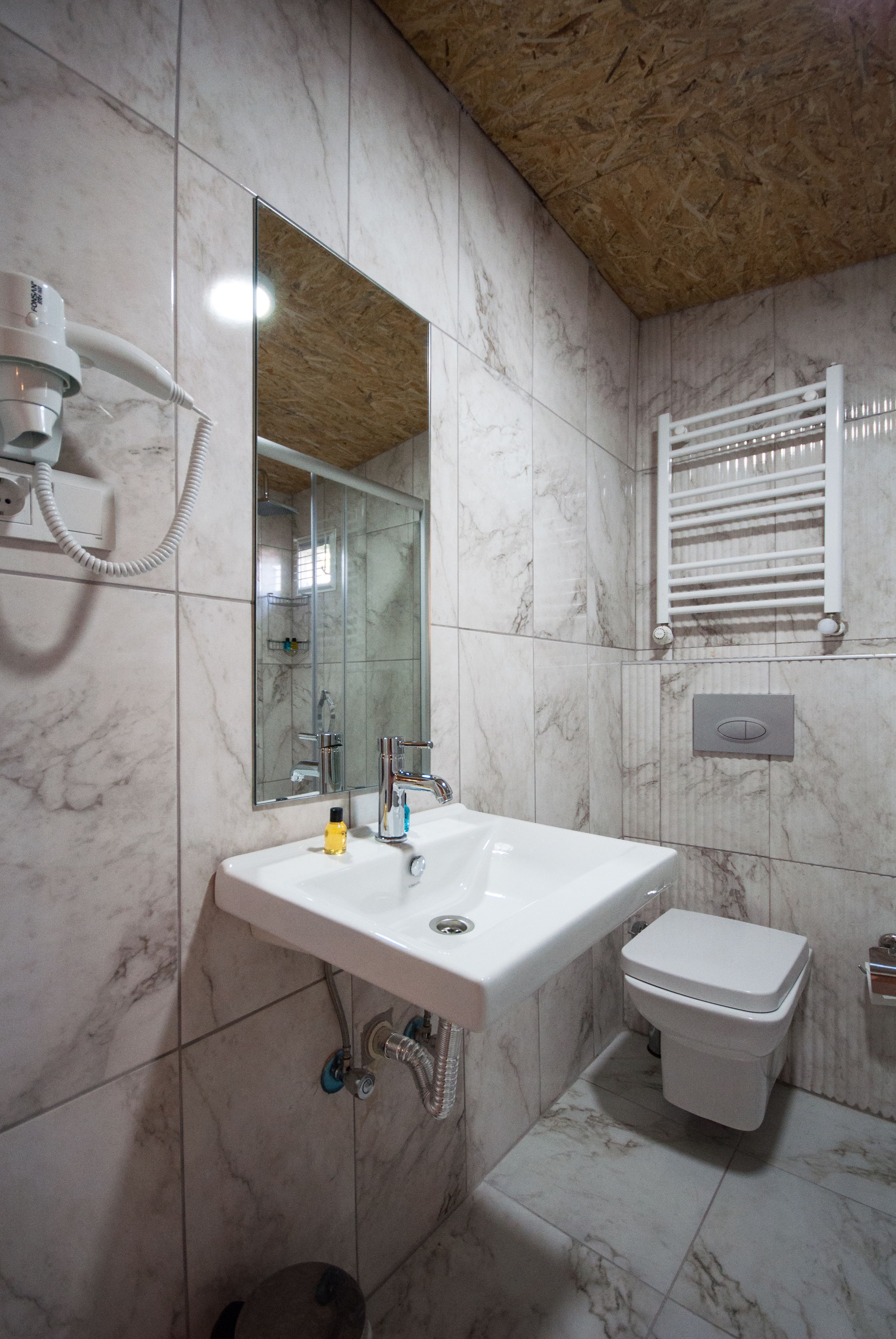 Une salle de bain avec un lavabo blanc, un miroir et des toilettes.