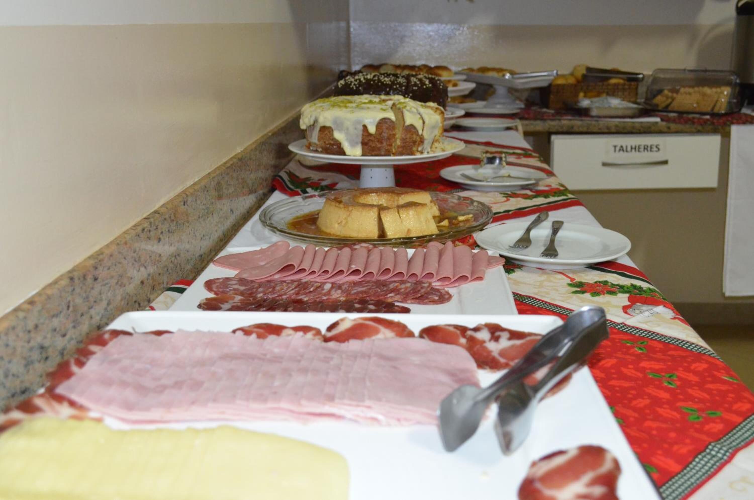 Une table de buffet proposant une variété de plats, notamment des viandes, des fromages et des desserts.