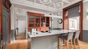 Una cucina moderna con isola centrale, mobili in legno e un orologio appeso al muro.
