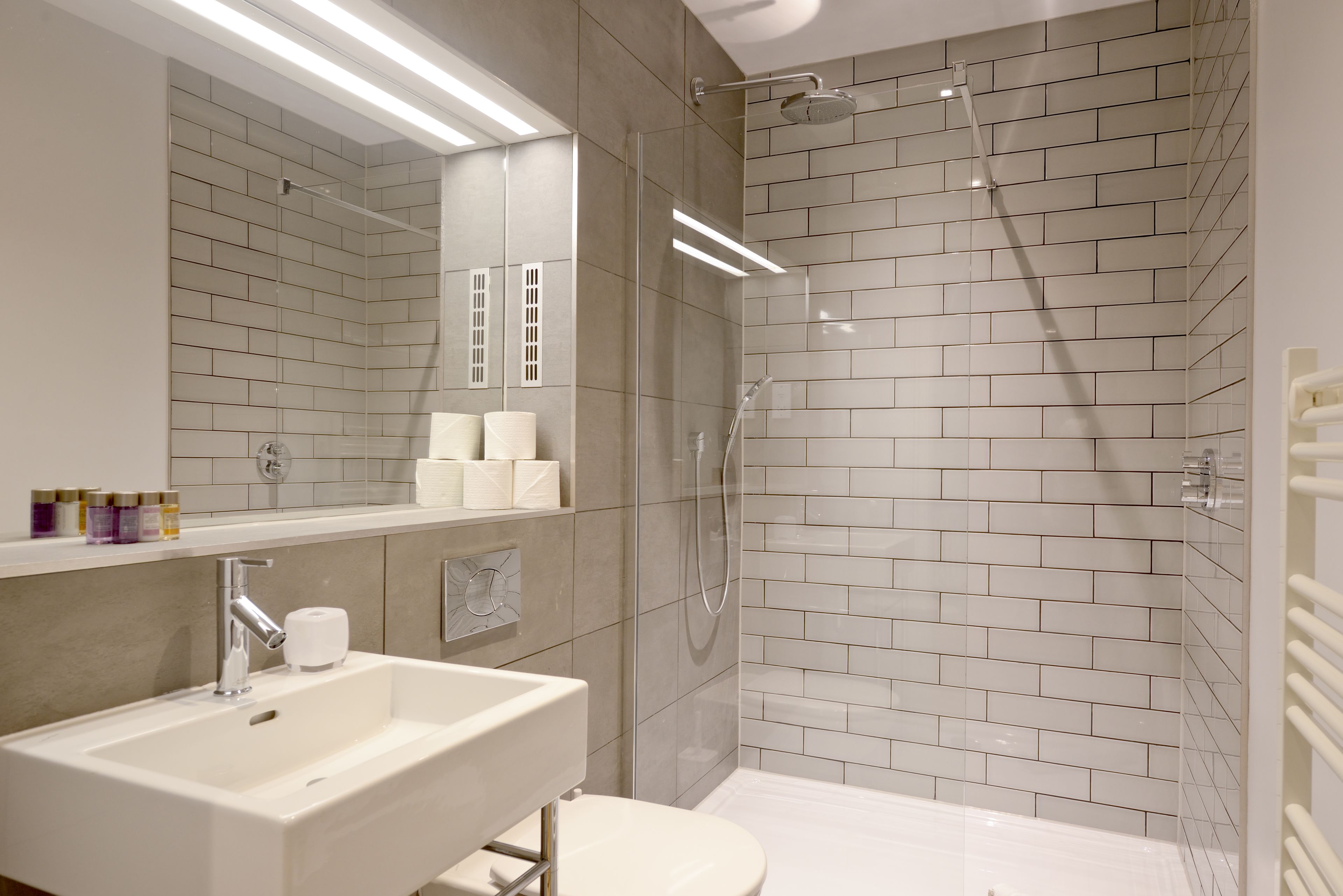 Une salle de bain moderne avec un lavabo blanc, un miroir et des toilettes.