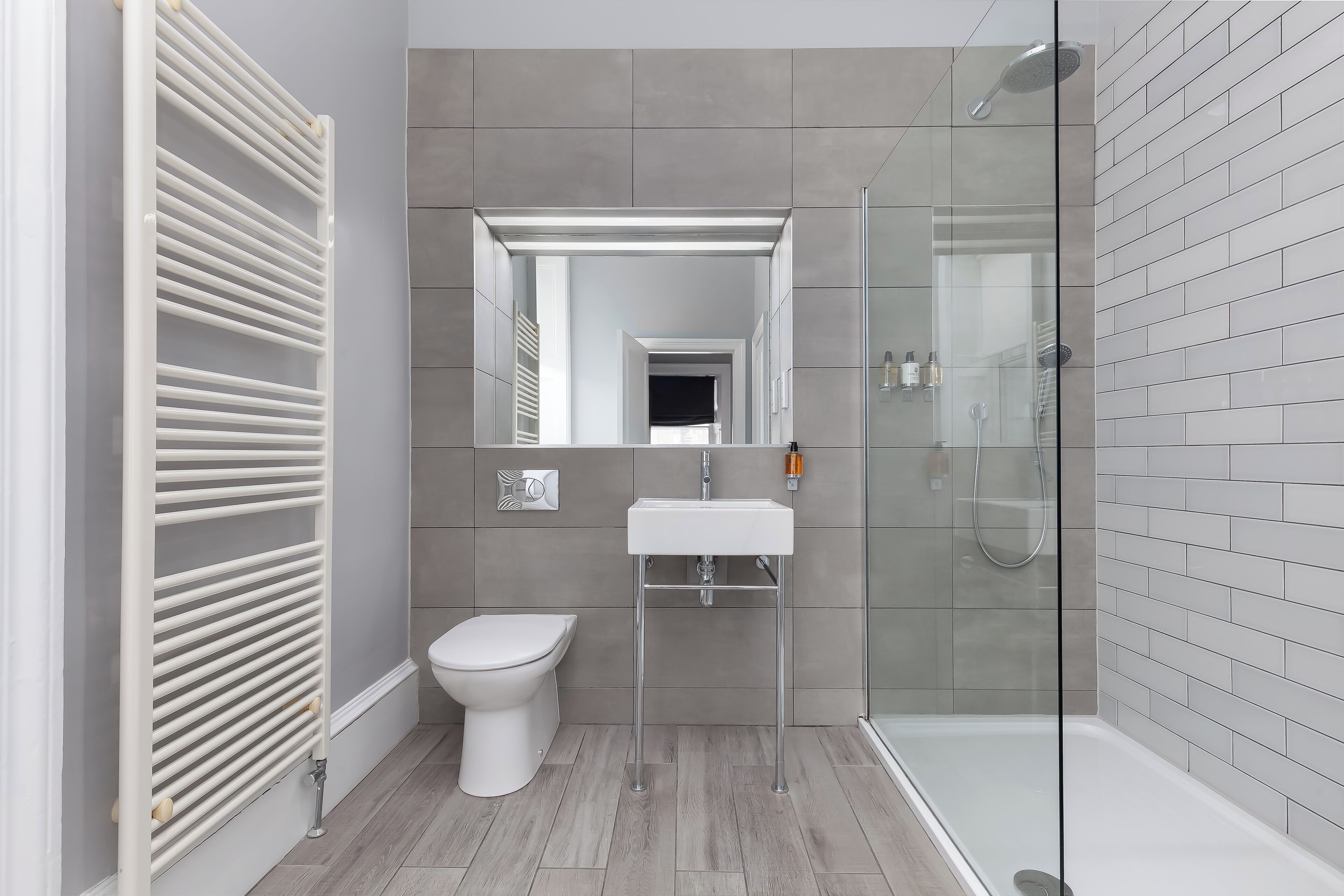A modern bathroom with a glass shower enclosure, a white toilet, and a sink with a mirror above it.