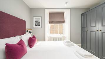 A bedroom with a large bed, white bedding, and a window with a view.