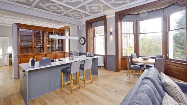 Una cucina moderna con isola centrale, mobili in legno e zona pranzo con tavolo e sedie rotonde.