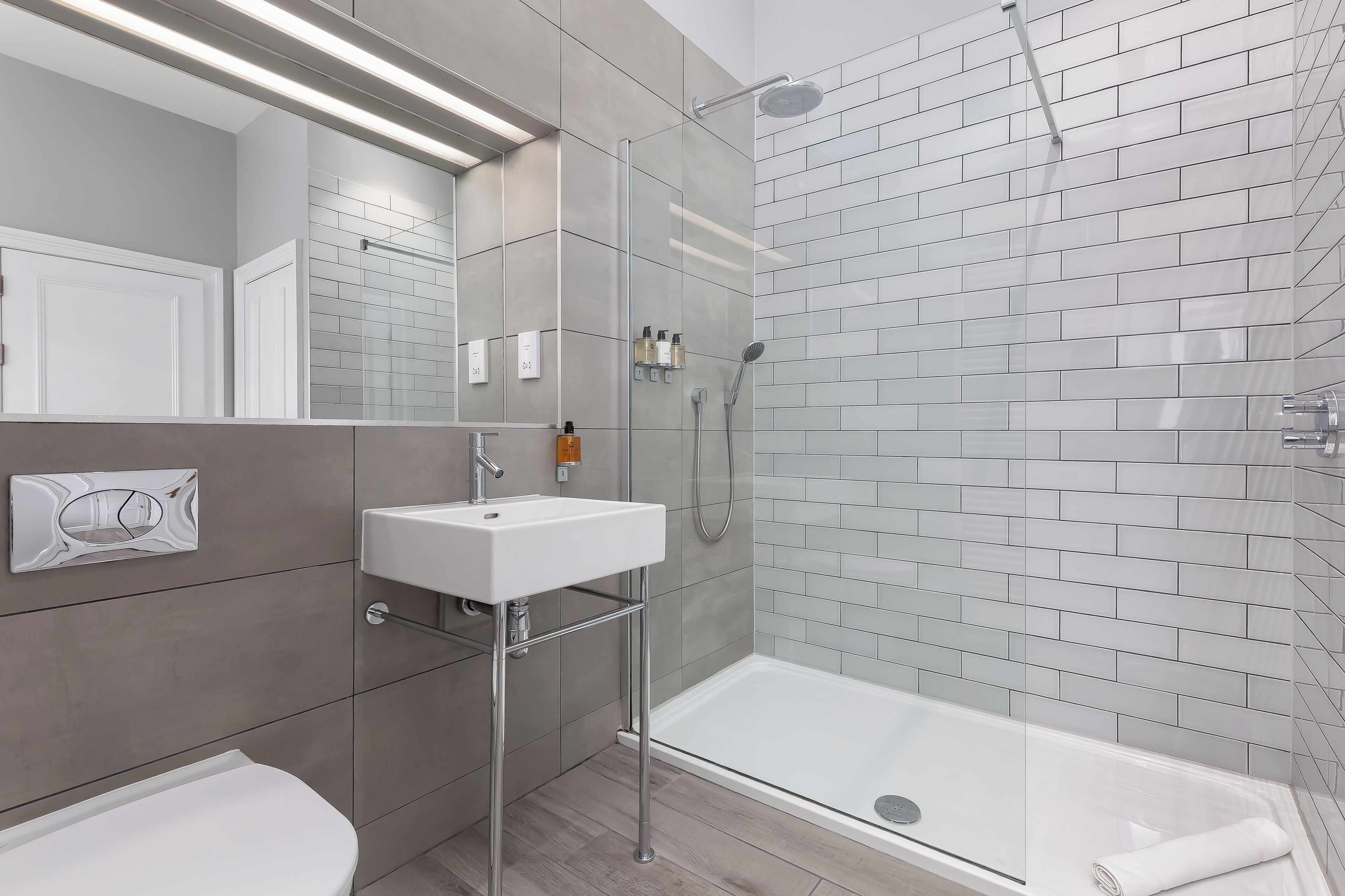 A modern bathroom with a glass-enclosed shower, a white sink, and a toilet.