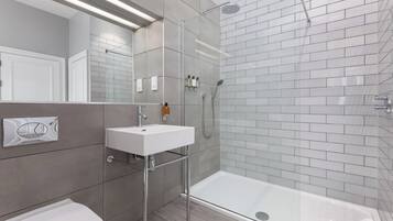 A modern bathroom with a glass-enclosed shower, a white sink, and a toilet.