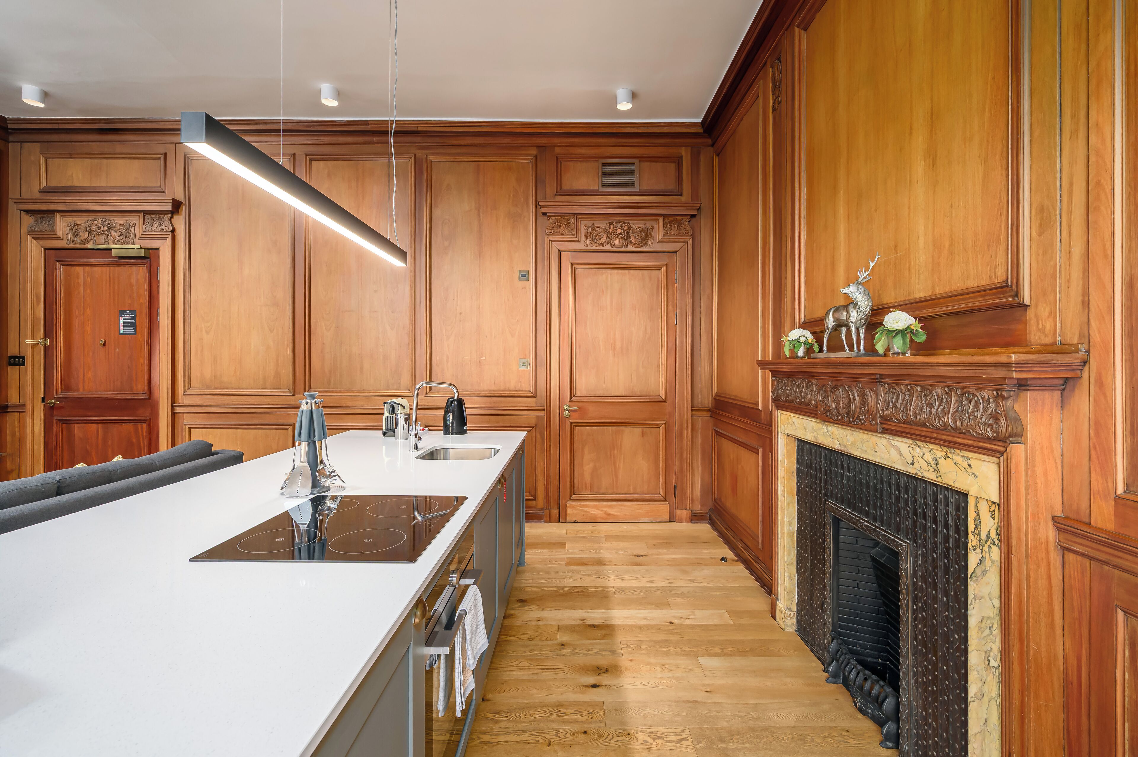 A modern kitchen with wooden cabinetry, a large island with a sink, and a fireplace.