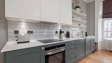 Een moderne keuken met grijze kastjes, een wit aanrecht en een inbouwoven.