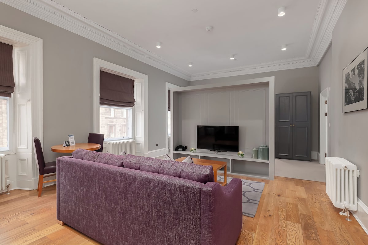 Una sala de estar moderna con un sofá modular, un televisor y un comedor.