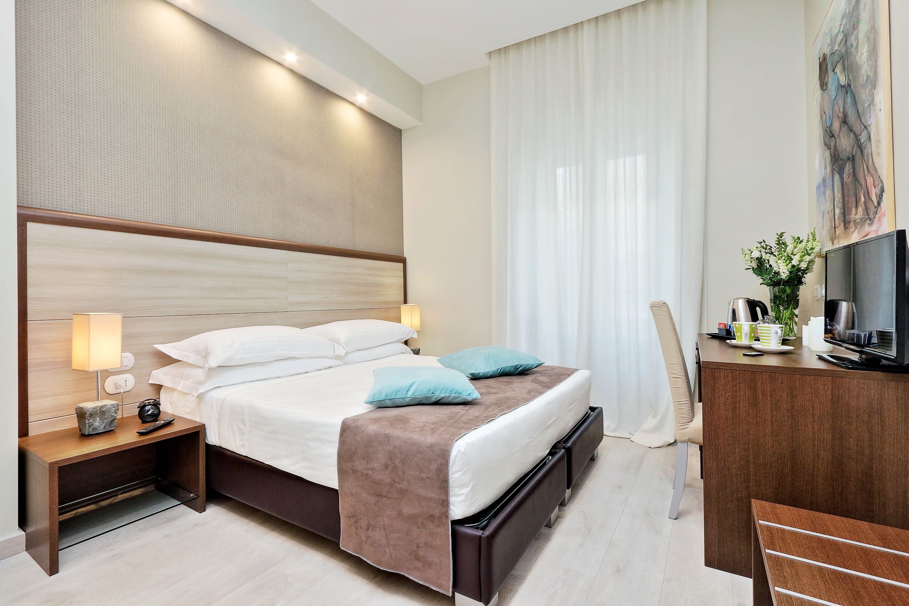 Ein Hotelzimmer mit einem großen Bett, Nachttischlampen, einem Fernseher und einem Schreibtisch mit Stuhl.