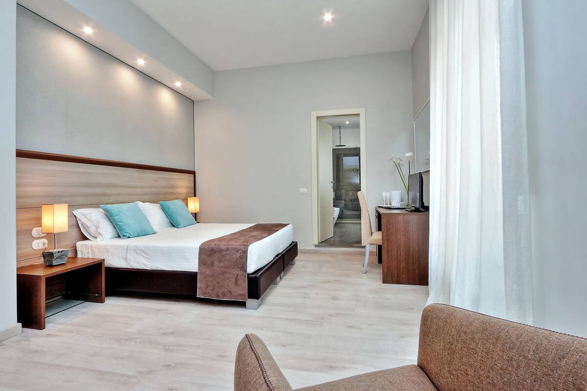 A modern hotel room with a large bed, bedside tables, a desk, and a chair.